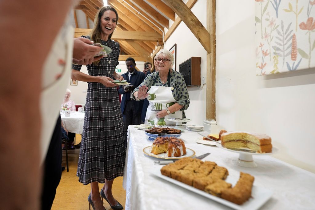Catherine, Princess of Wales looks at the cakes on table laughing