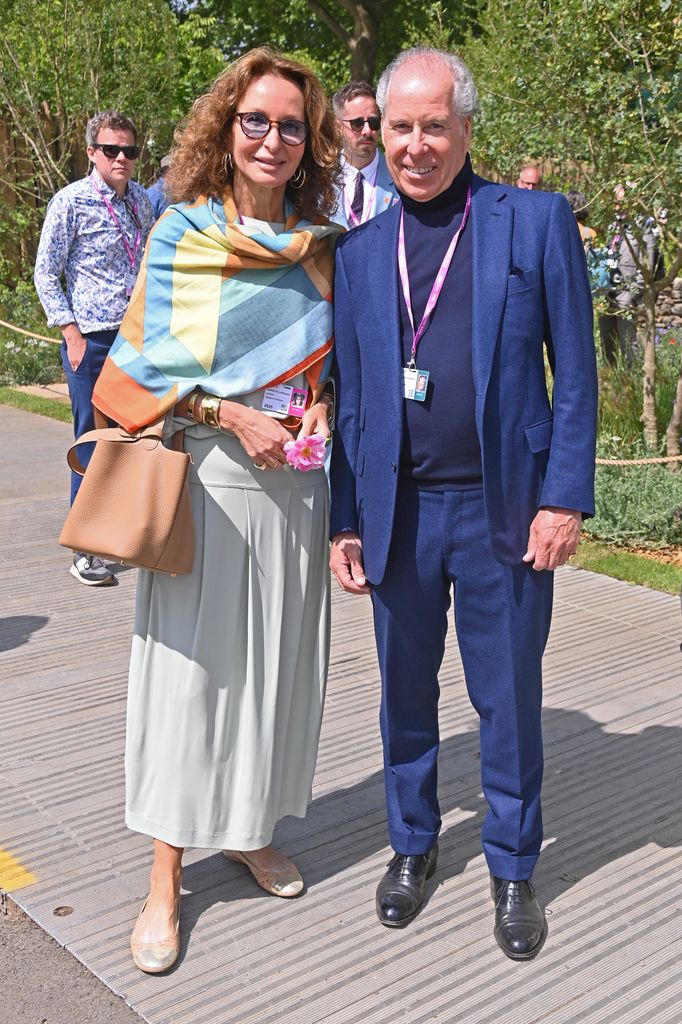 Isabelle Chopin De La Bruyere wears a pastel geometric shawl and flowing skirt stands with David Armstrong-Jones, 2nd Earl of Snowdon wearing a navy suit at Chelsea Flower Show 2025.