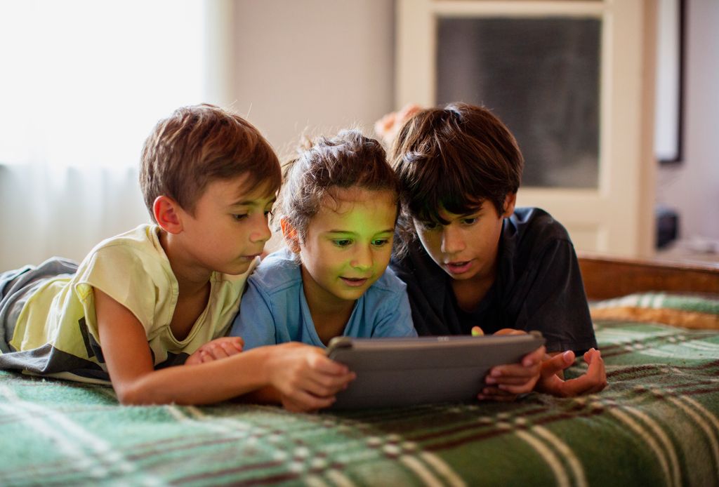boys and girl using a digital tablet, lying on bed