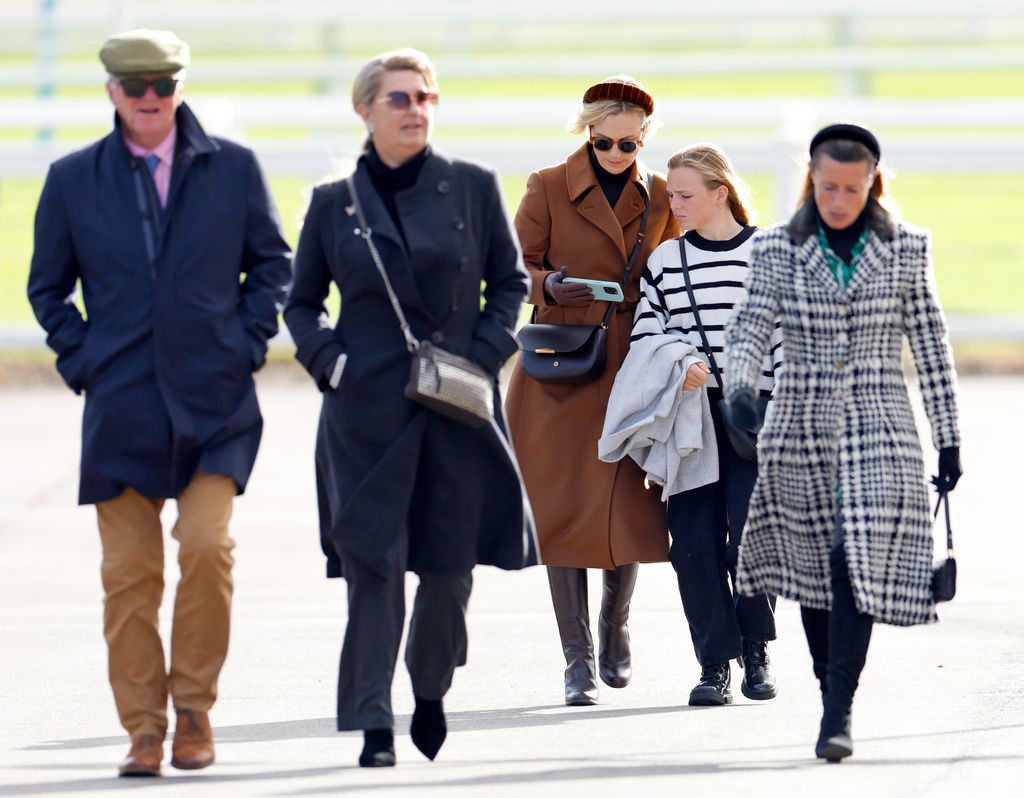 Zara Tindall and her daughter Mia looking at phone walking behind people