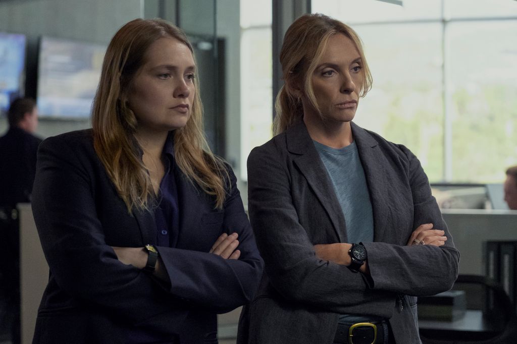 two women with arms folded in office