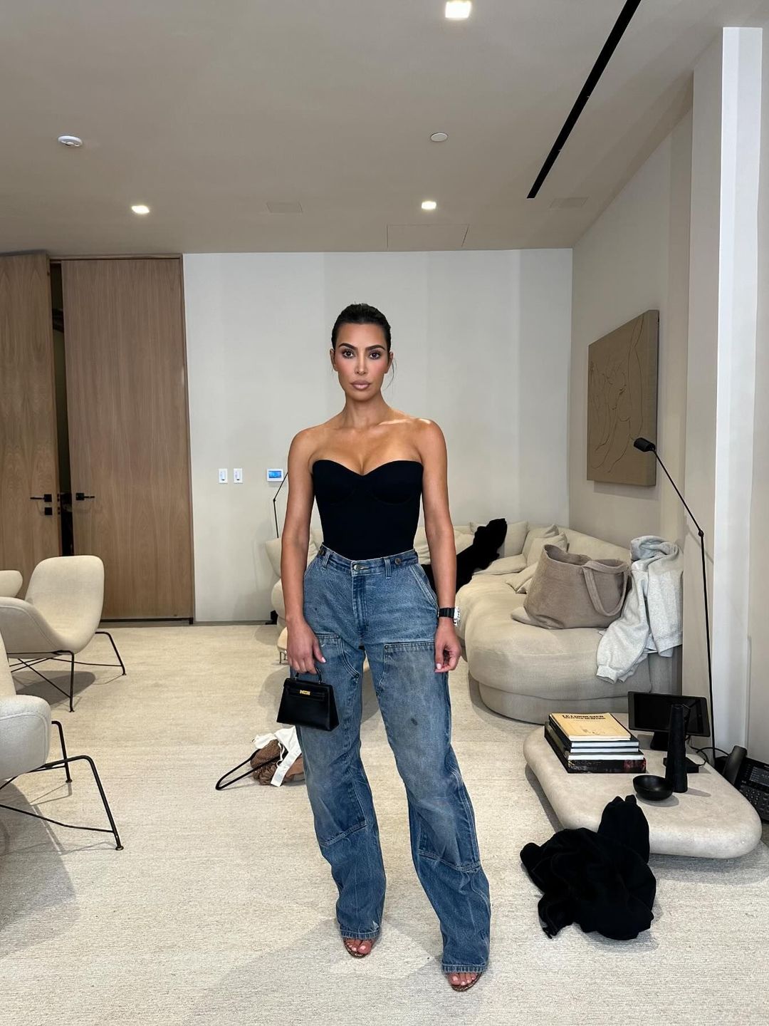 Kim Kardashian wears blue jeans and a tight black corset top