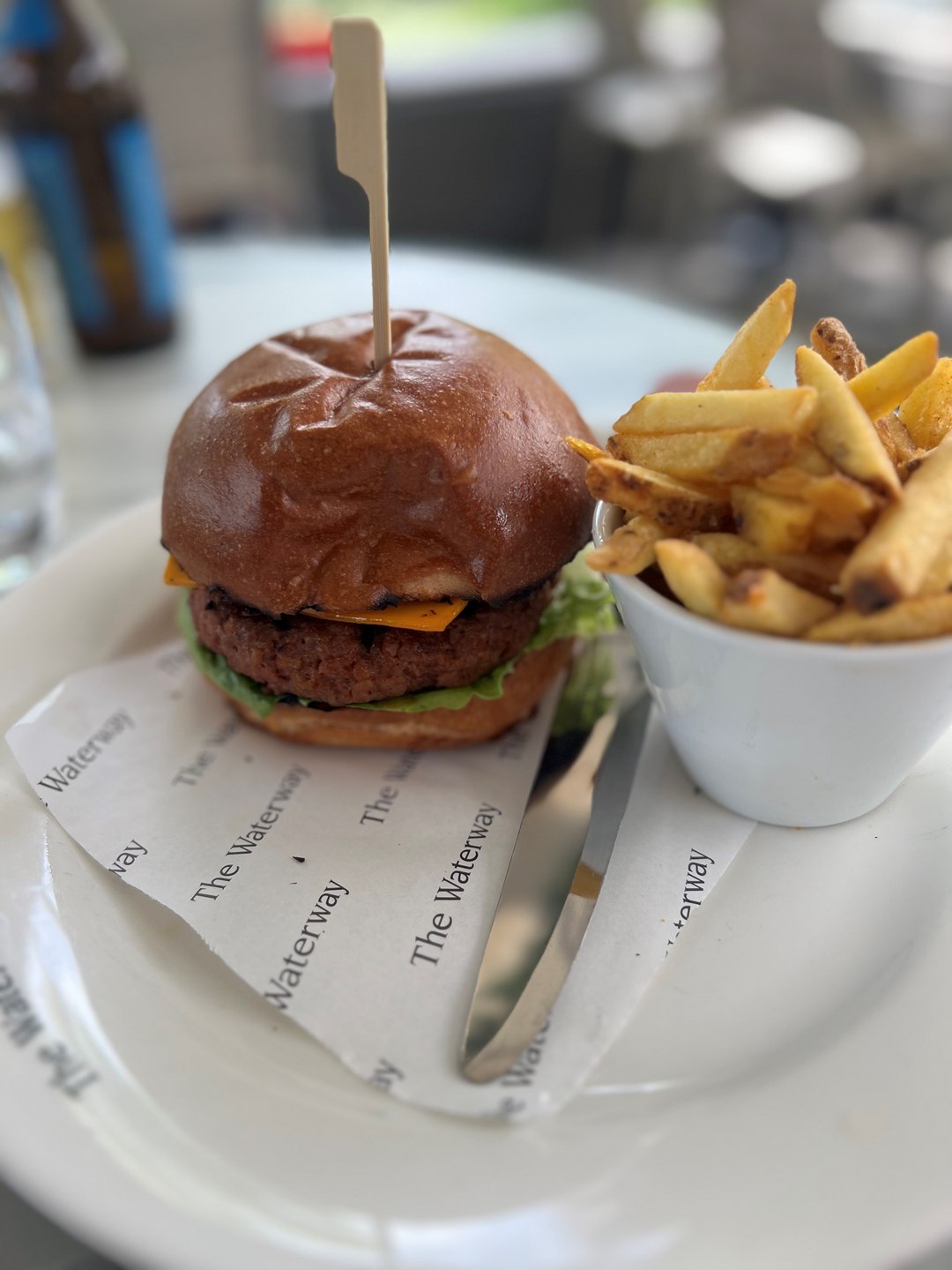 A burger sat next to a small bowl of chips
